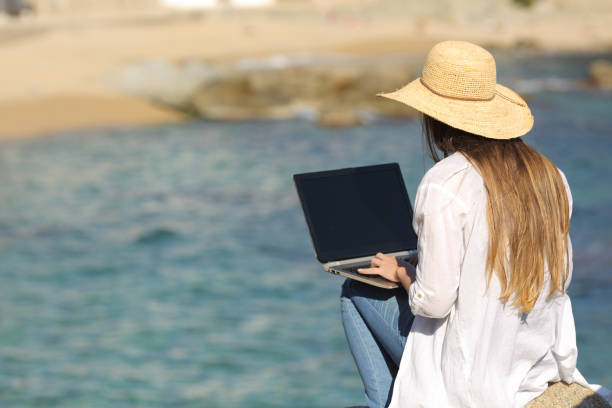 Woman typing on her laptop on the beach